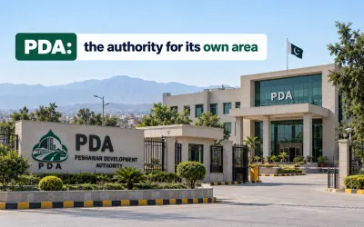 Exterior view of the Peshawar Development Authority (PDA) headquarters building with its entrance sign, Pakistani flag, and distant mountains under a clear blue sky.