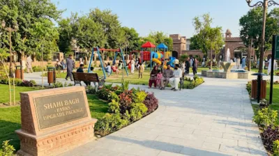 A bright, eye-level photograph of a modern, upgraded community park in Peshawar with families, children playing on equipment, and a "Parks Upgrade Package" plaque.