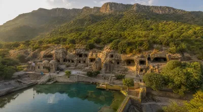 Aerial view of the Shah Allah Ditta Caves nestled at the base of the lush green Margalla Hills in Islamabad, Pakistan — a 2,400-year-old Buddhist heritage site central to Pakistan's cultural diplomacy strategy.