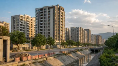 Modern multi-storey apartment buildings beside a concrete drainage channel with roads and the Margalla Hills in the background.