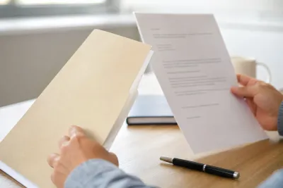 Close-up of hands reviewing property documents and a transfer letter on a desk.