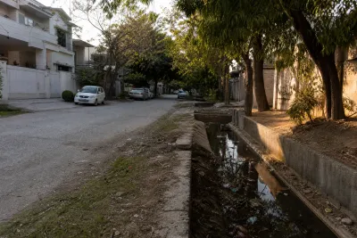 Residential street in a cooperative housing society block in E-11 Islamabad, with a drainage channel beside the road.