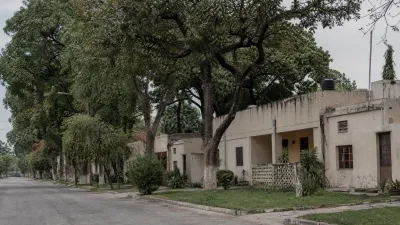 Row of aging single-storey government quarters with mature trees in an older Islamabad sector.