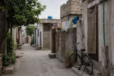 Narrow residential lane in an informal settlement in Islamabad with modest brick homes.