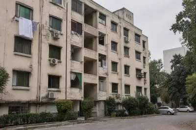 Weathered mid-rise residential apartment block with window air-conditioning units and laundry lines, Islamabad.
