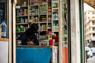 Small general store or pharmacy shopfront with visible shelves inside a Markaz commercial building.