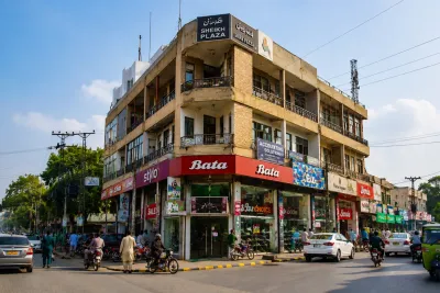 Corner commercial shopfront with dual street visibility in an Islamabad Markaz at golden hour.
