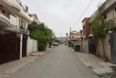 Densely spaced residential street in an Islamabad G-sector with commercial activity visible in the background.