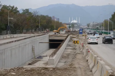 Road construction site with barriers and machinery along a highway corridor in Islamabad.
