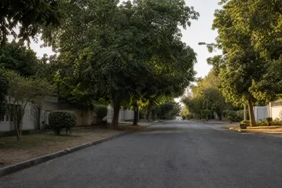 Spacious tree-lined residential street with large boundary walls in an Islamabad F-sector.
