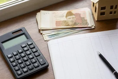 Calculator, rupee notes, and a rent ledger on a desk, photographed from above.