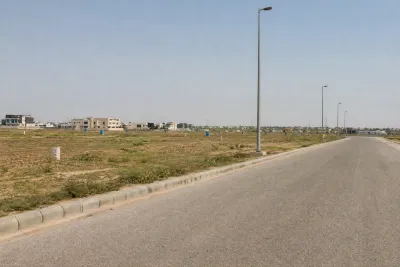 Empty residential plots with paved road and streetlight poles but no houses built, in a newer Islamabad housing sector.