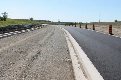 Partially completed service road with asphalt on one side and unfinished gravel on the other, in an Islamabad housing sector.