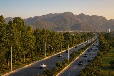 Wide avenue with clear lane markings and Margalla Hills visible in the background at golden hour.