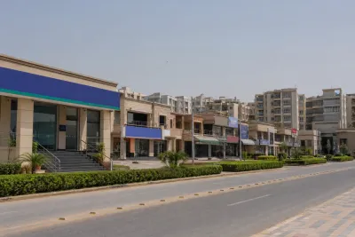 Residential street with a mix of completed and grey-structure houses on evenly spaced plots.