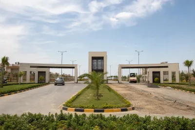 Modern gated entrance with a landscaped boulevard leading into a housing scheme.