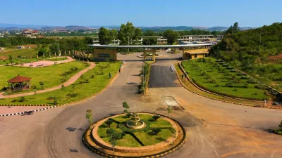 Landscaped residential society entrance in Rawalpindi with wide roads, green lawns and surrounding development.