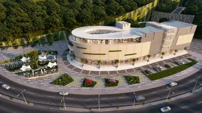 Aerial view of a modern commercial complex surrounded by landscaped areas, parking, and tree-covered hills.