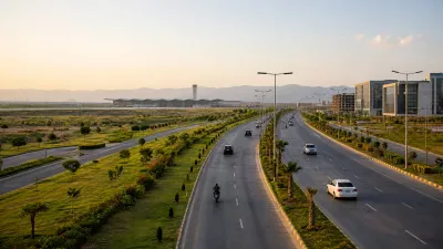 Wide landscaped road near Islamabad International Airport, with light traffic, modern commercial buildings, green medians, and the Margalla Hills visible in the background.