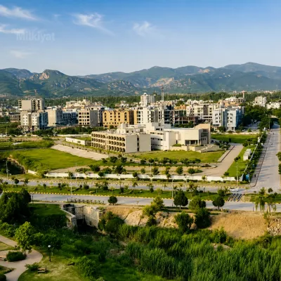 Aerial view of B-17 Islamabad showing developed roads, landscaped areas, residential and commercial buildings, and the Margalla Hills in the background.