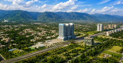 Aerial view of Islamabad’s developed urban areas, highways, modern buildings, and residential neighborhoods with the Margalla Hills in the background.