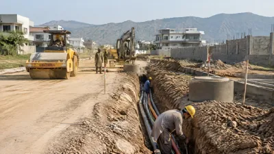Construction workers installing underground utility lines beside a newly formed road in DHA Margalla Enclave.